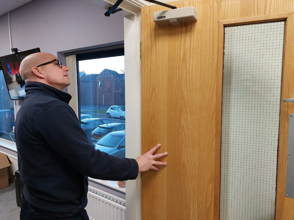 Qualified fire door inspector, inspecting a fire door in a care home